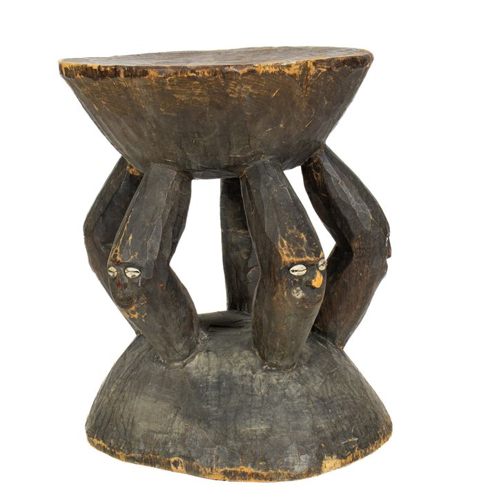 A Papua New Guinea Sepik River stool on figural supports with inset cowrie shells