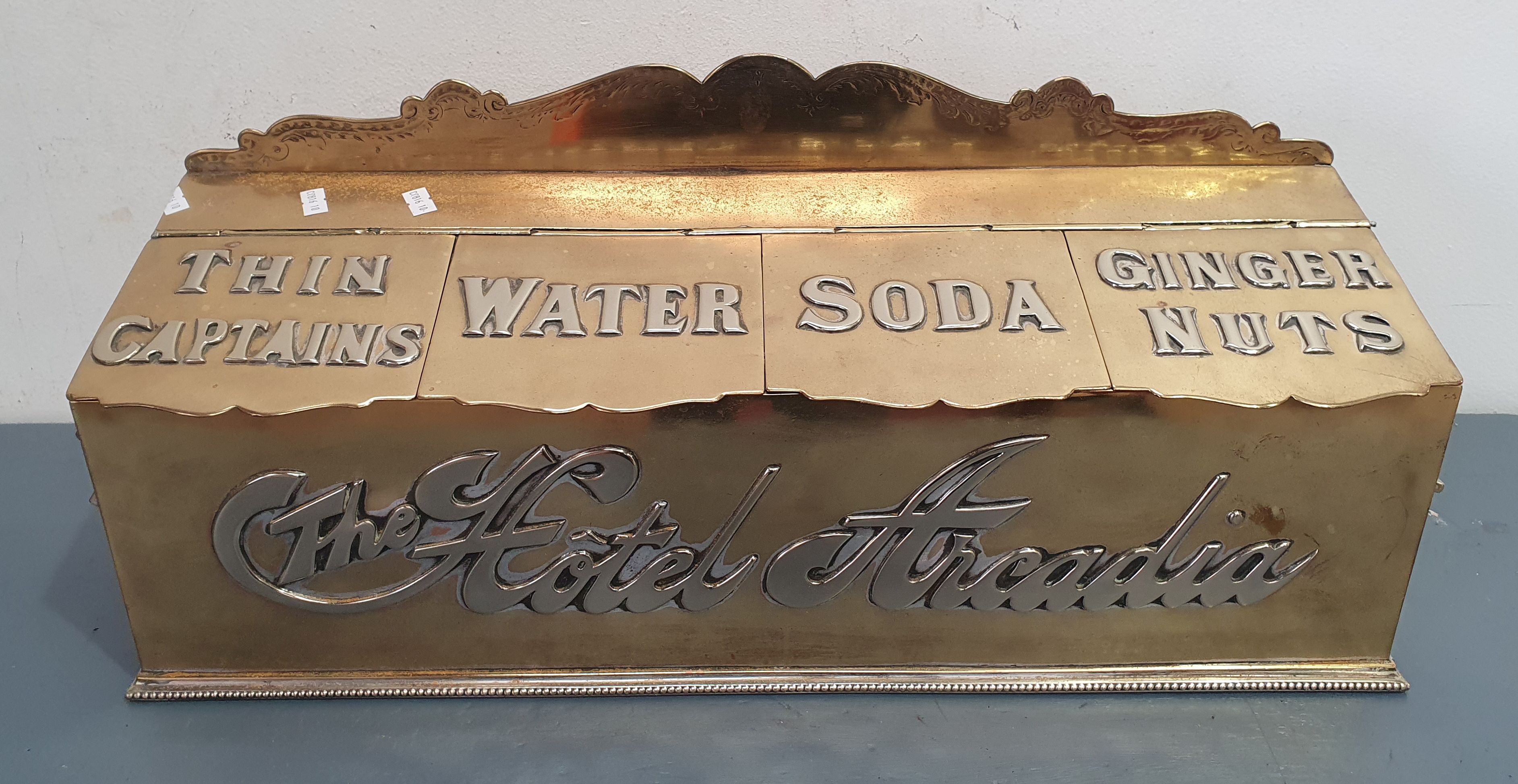 A BRASS 'HOTEL ARCADIA' BISCUIT BOX BY ALFRED CRESSWELL