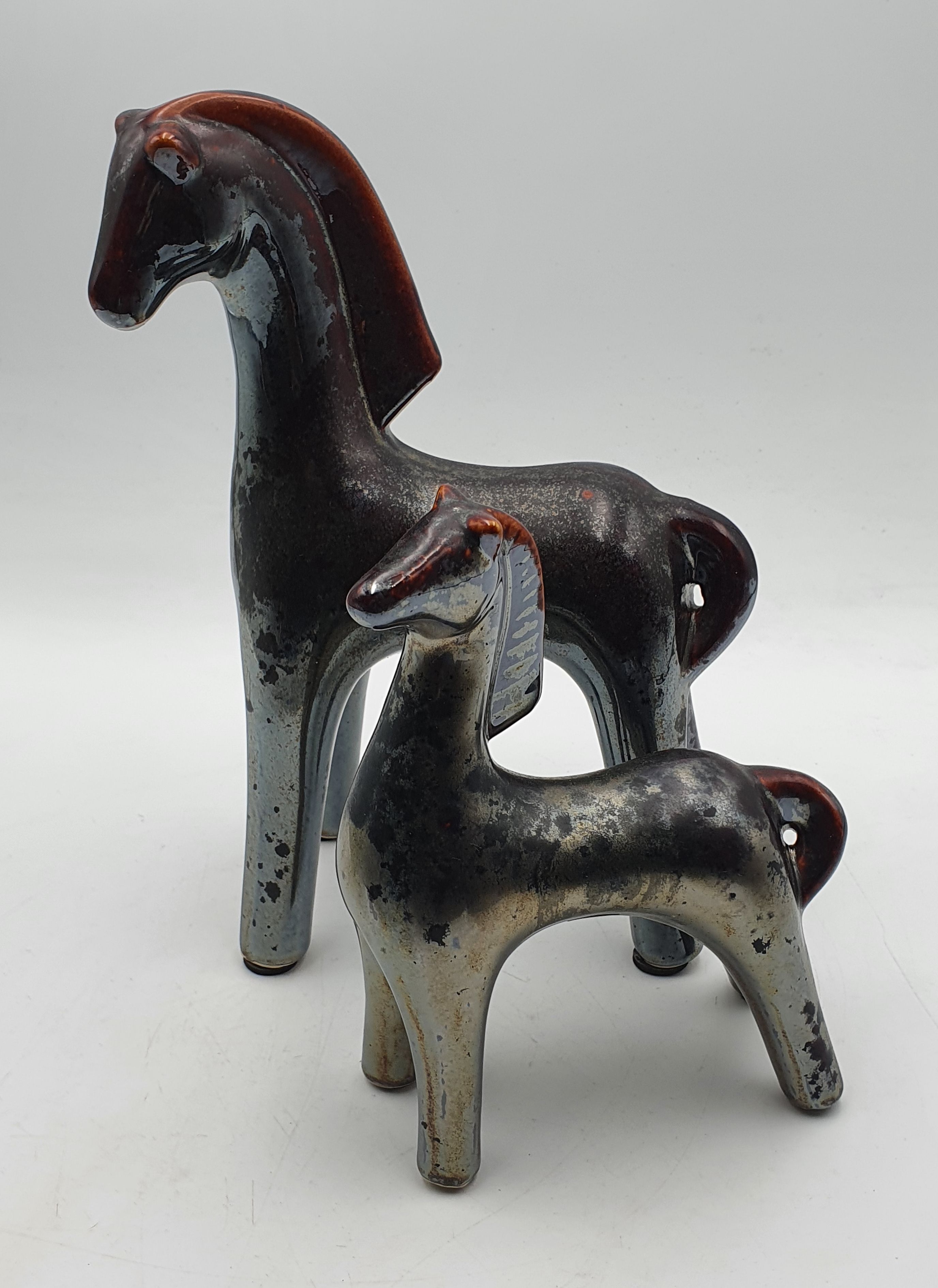 214 · A GRADUATED PAIR OF STYLISED IRIDESCENT GLAZED POTTERY HORESE