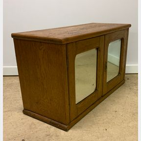 TWO DOOR OAK CABINET WITH BEVELED MIRRORED GLASS DOORS.