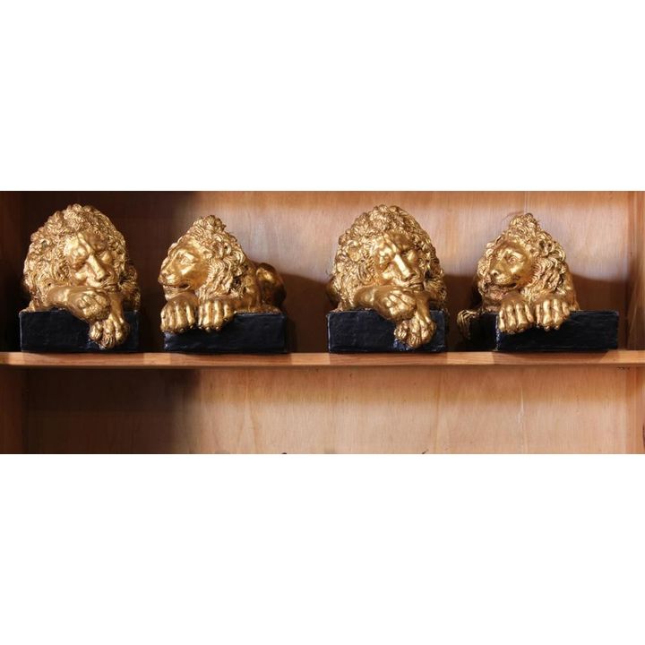 Neo-Classical style composite reclining lion statues, each rising on a black painted plinth