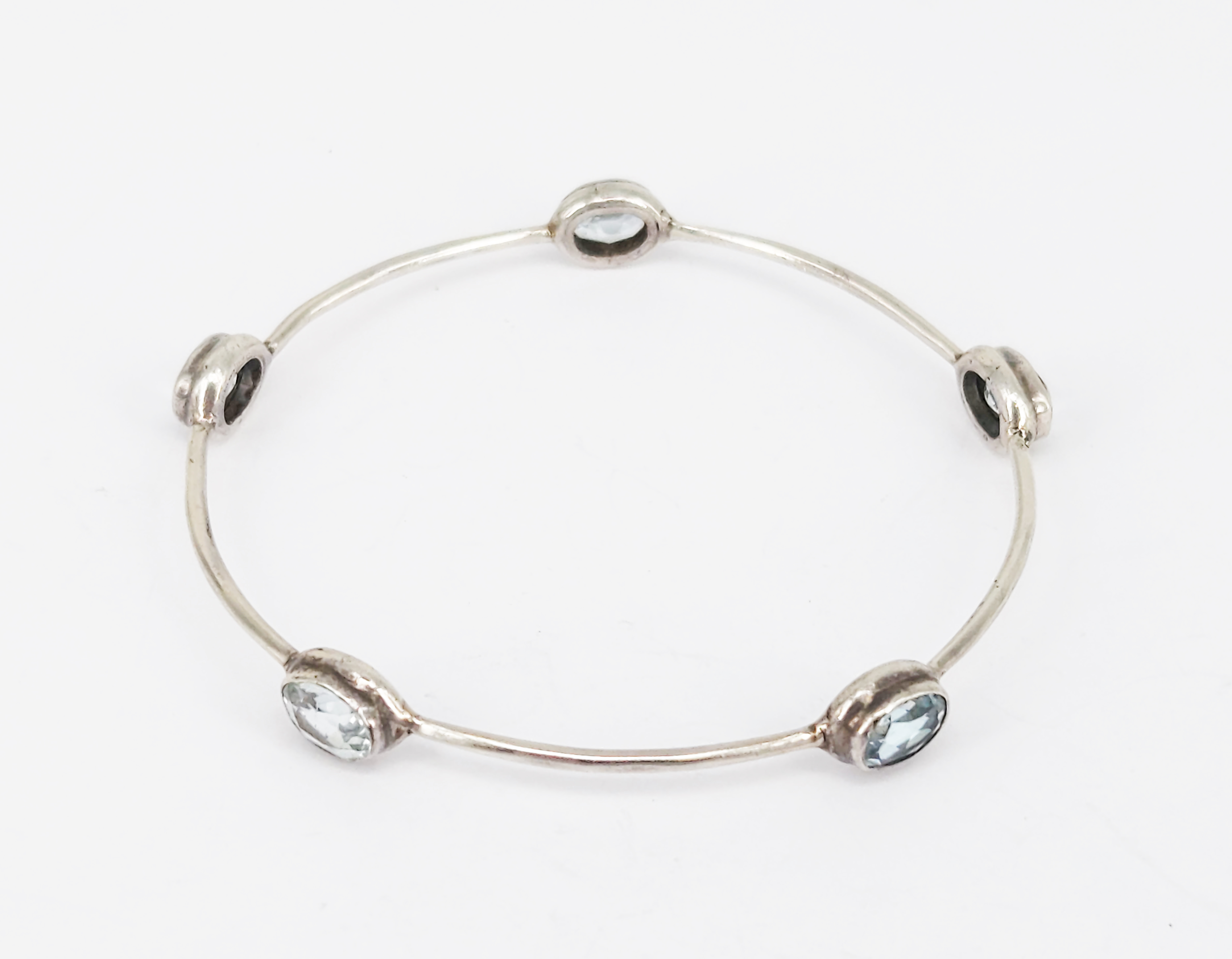 353 · A SILVER AND FIVE-STONE TOPAZ BANGLE