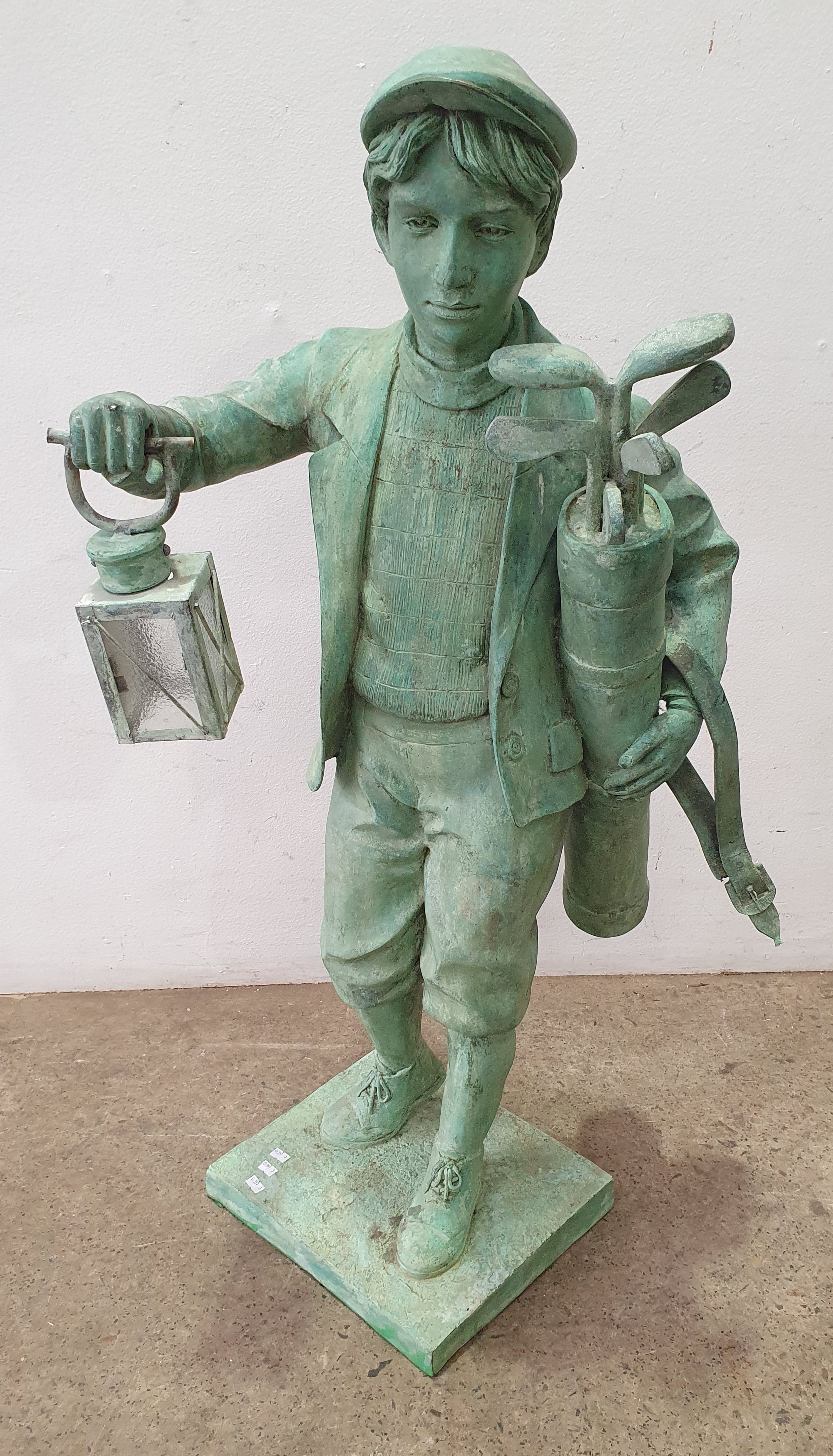A Bronze Statue Of A Boy Golf Caddy