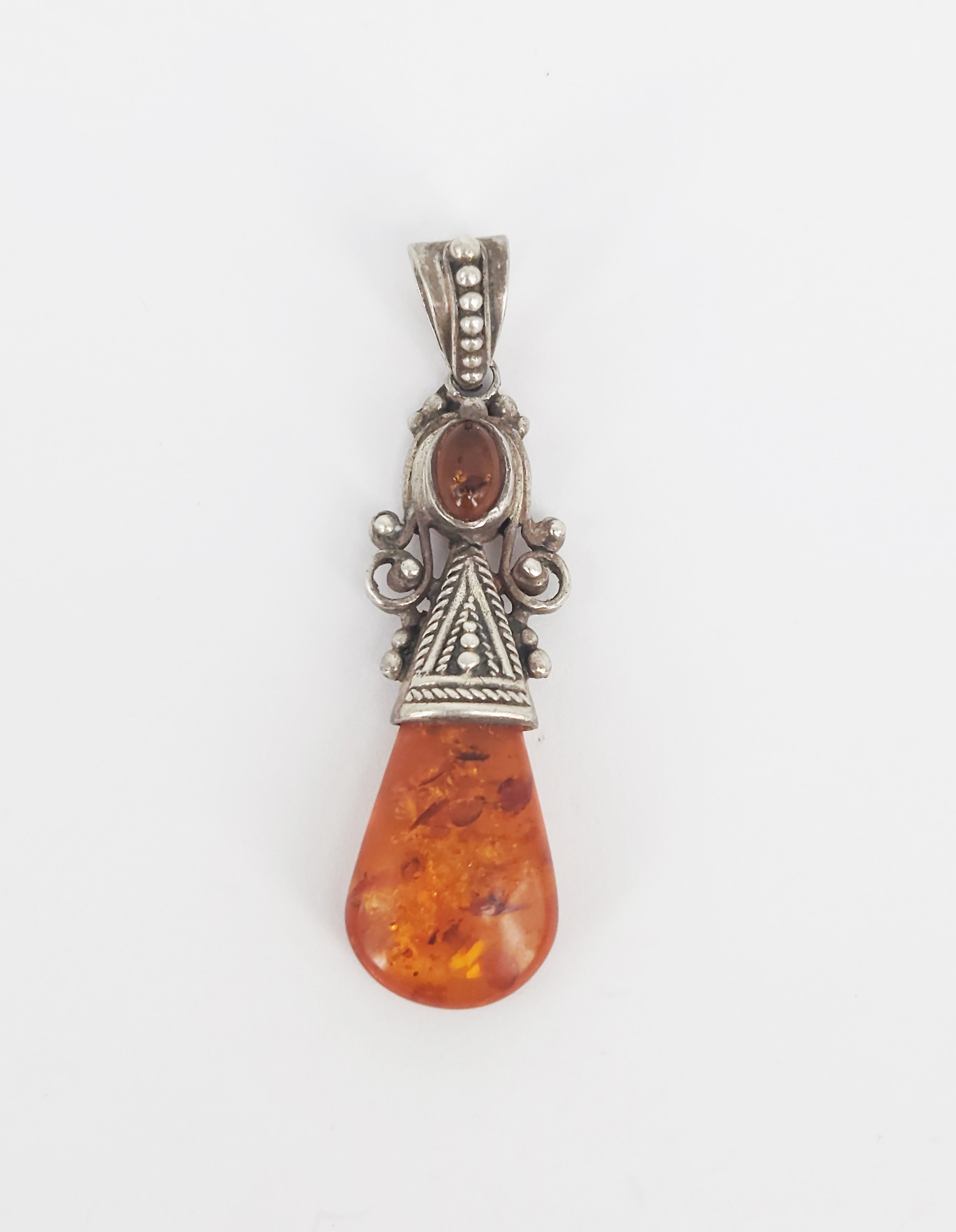 442 · A TIBETAN STYLE SILVER AND AMBER PENDANT
