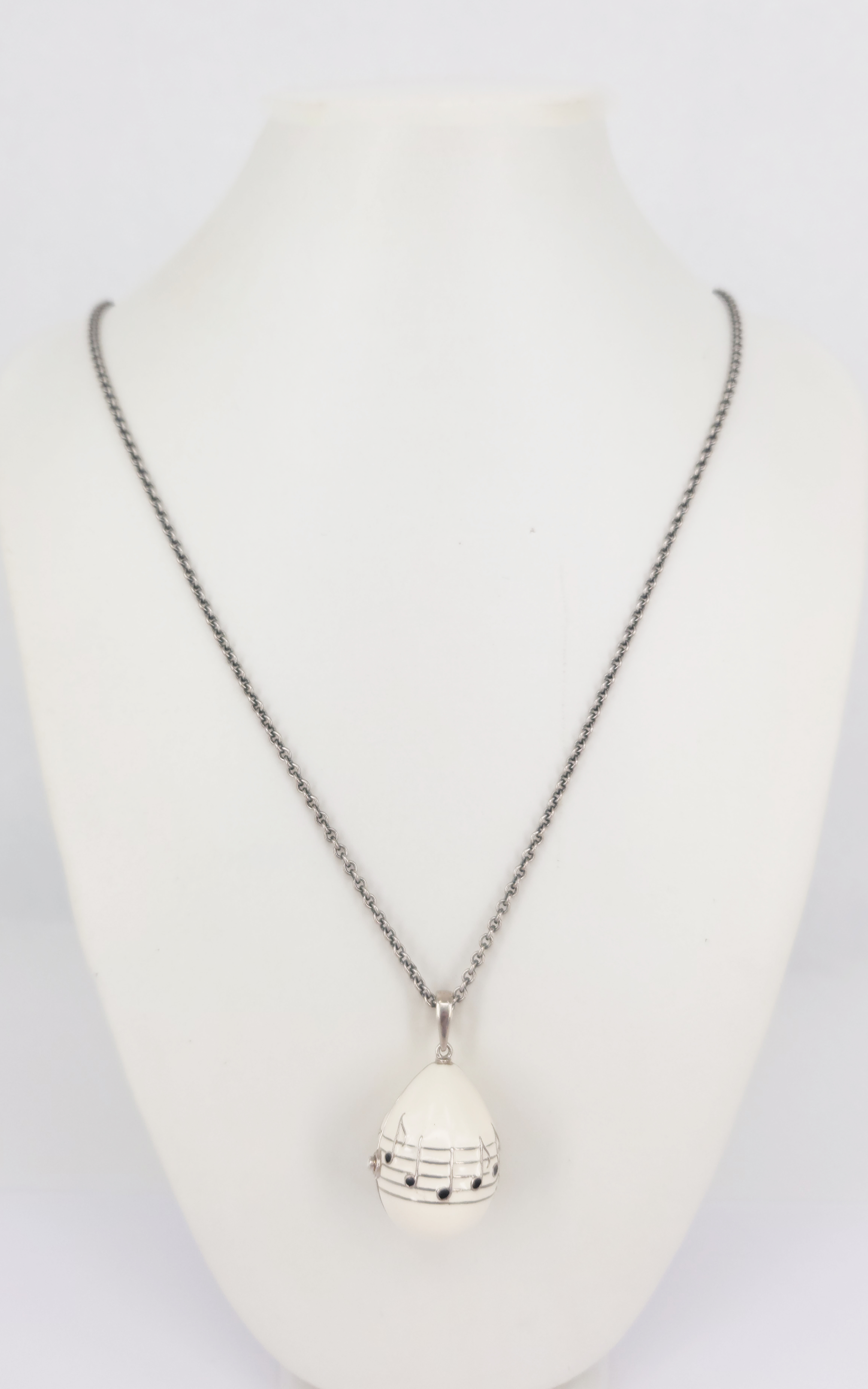 436 · A STERLING SILVER BLACK AND WHITE ENAMEL MUSICAL EGG LOCKET PENDANT