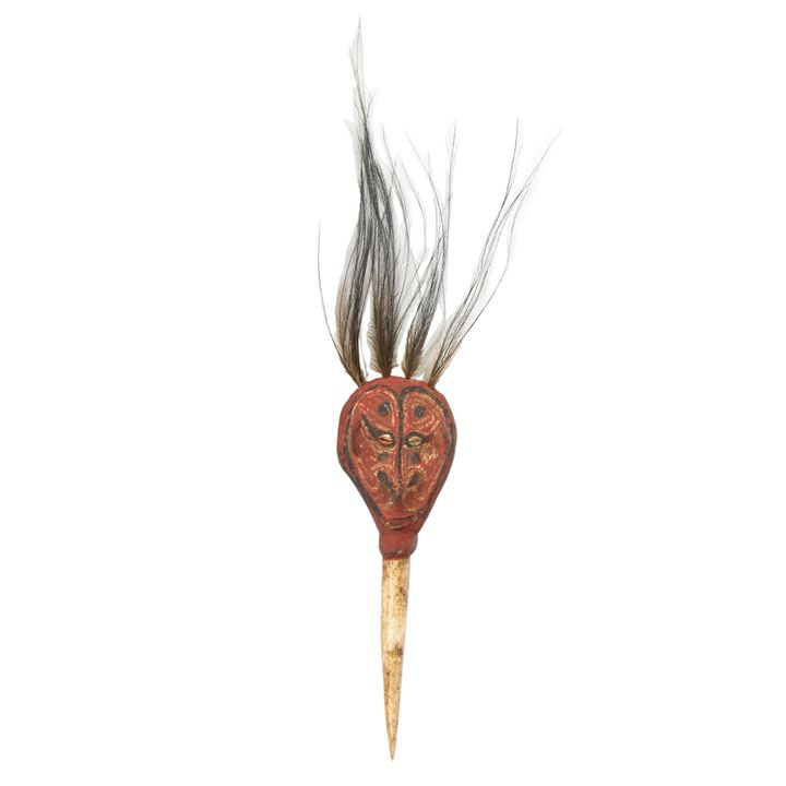 An Asmat bone dagger with a head form handle embellished with feather tassels