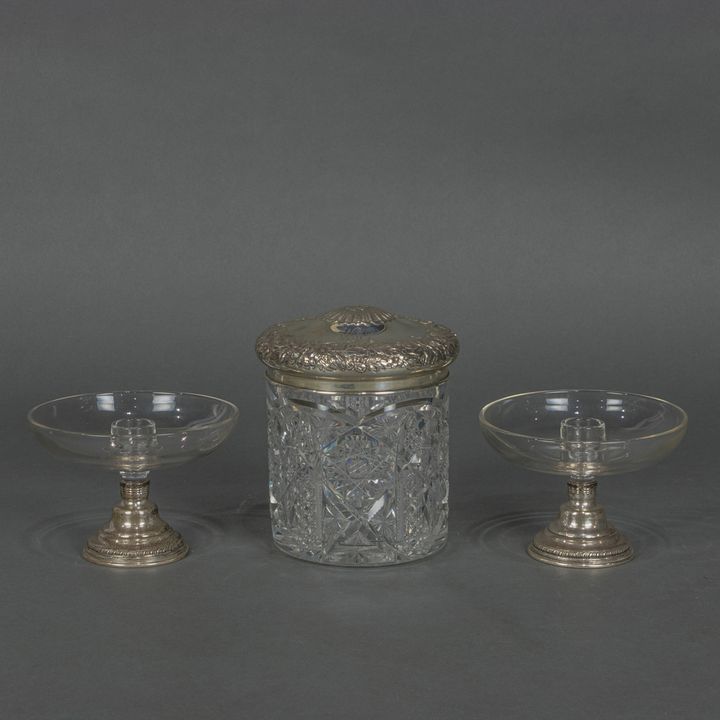 An Art Nouveau sterling floral repousse lidded cut glass cigar box; en suite with a pair of glass bowl form candle holders
