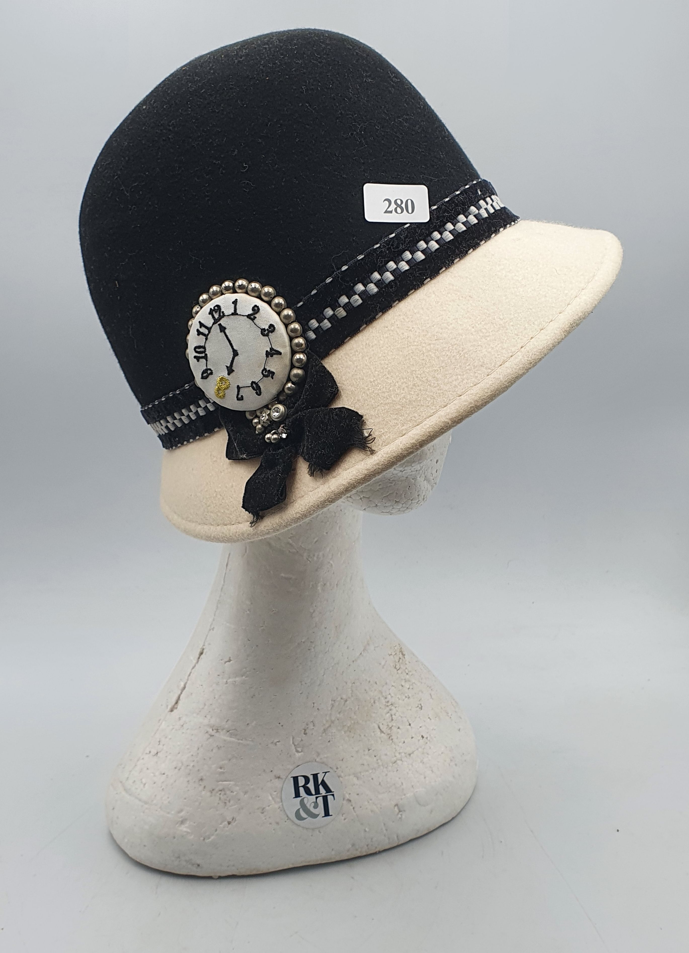 280 · A LADIES BLACK AND WHITE WOOL HAT WITH CLOCK EMBELLISHMENT